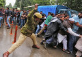 Индийский полицейский использует дубинки для разгона демонстрантов во время акции протеста государственных служащих, требующих изменений трудового законодательства.