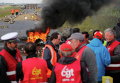 Протестующие работники профсоюзов стоят возле горящей баррикады, которая блокирует вход в топливное депо SFDM вблизи нефтеперерабатывающего завода Donges, Франция