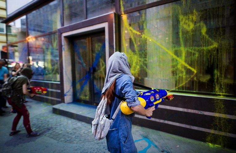 Протестующие в масках используют водяные пушки для распыления краски во время антиправительственного протеста в Скопье