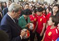 Государственный секретарь США Джон Керри подписывает футбольный мяч рядом с вице-премьер Китая Лю Яньдун в женской футбольной команде Пекинского педагогического университа