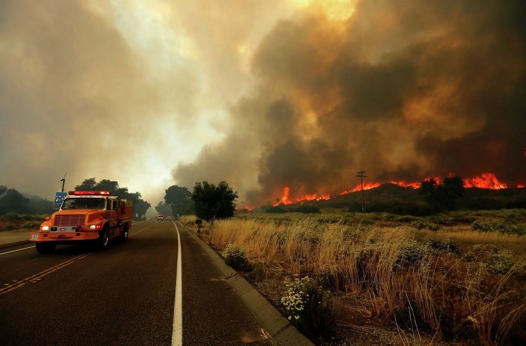 Пожарный вертолет борется с крупным пожаром, охватившим часть штата Калифорния