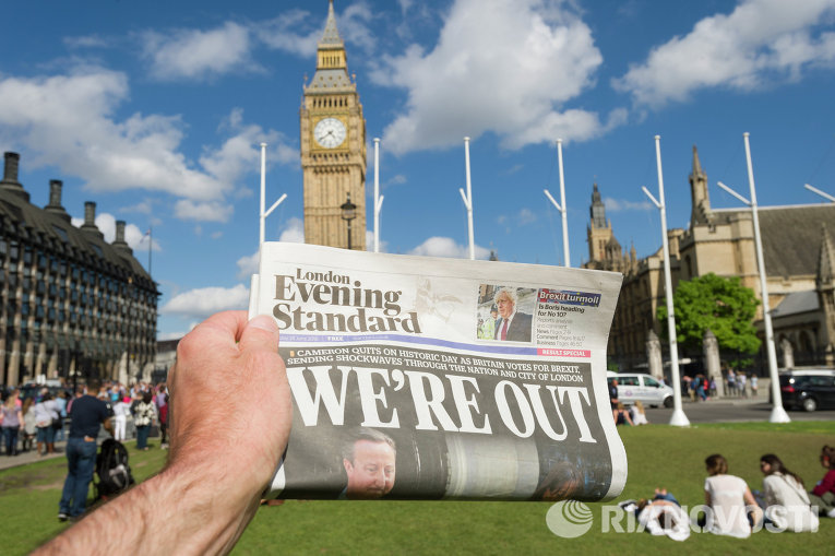Мужчина держит в руке газету у здания парламента в Лондоне после референдума