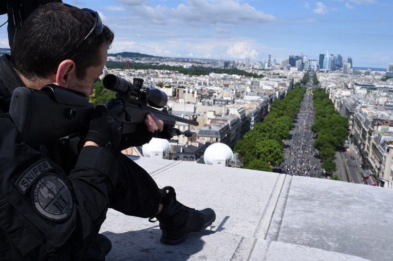 Снайпер занимает свою позицию в верхней части Триумфальной арки во время ежегодного военного парада в День взятия Бастилии на Елисейских полях в Париже
