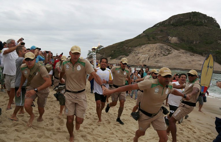 Бразильский серфер Рико де Соза несет олимпийский факел в Рио-де-Жанейро, Бразилия. Олимпийские игры стартуют 5 августа