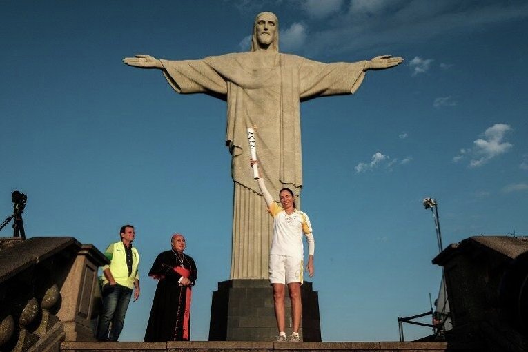 Бывшая бразильская волейболистка Мария Исабель Баррозо Сальгадо вместе с мэром Рио-де-Жанейро и архиепископом города, подняла Олимпийский огонь к статуе Христа Спасителя.