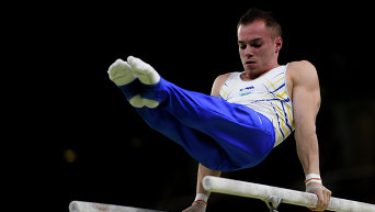 Олег Верняев выполняет упражнения на брусьях на соревнованиях по спортивной гимнастике среди мужчин