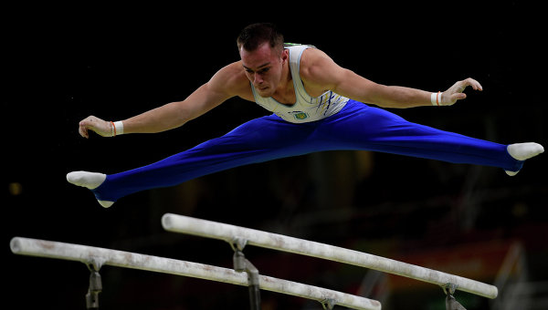 Олег Верняев выполняет упражнения на брусьях на соревнованиях по спортивной гимнастике среди мужчин