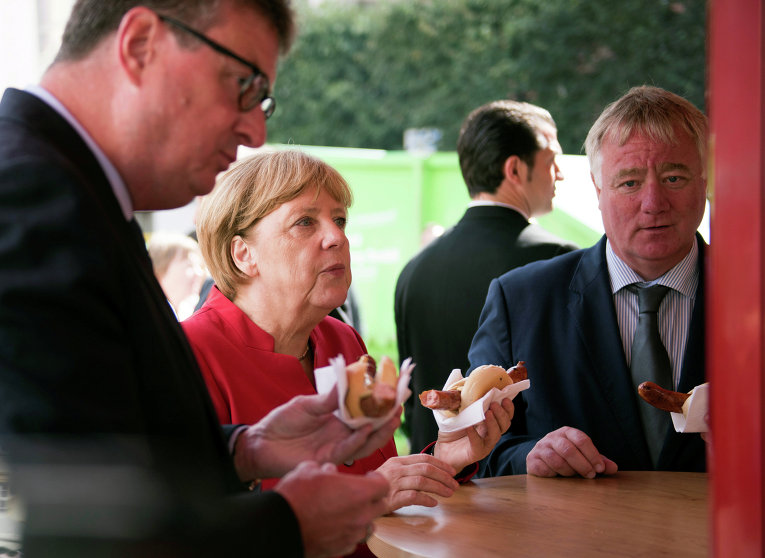 Канцлер Германии Ангела Меркель перекусывает хот-догами на рынке в Грайфсвальде, Германия.