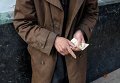 Пожилой человек считает деньги в центре Киева