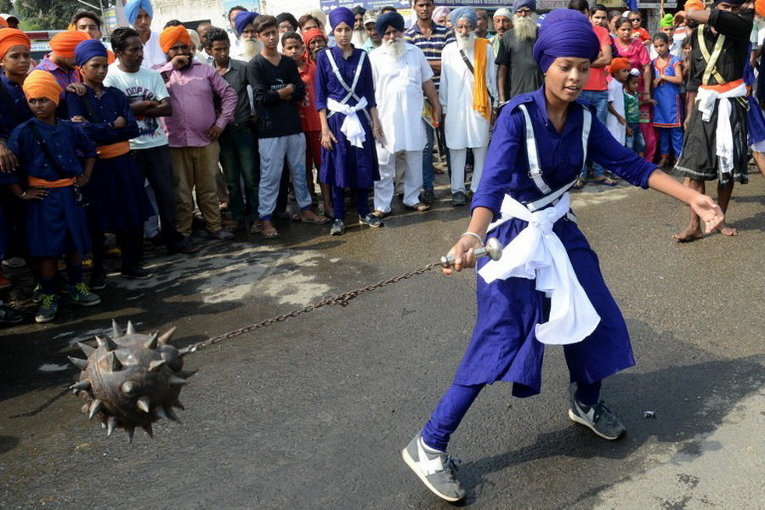 Девушка демонстрирует навыки боевых искусств во время шествия в Батала, Индия