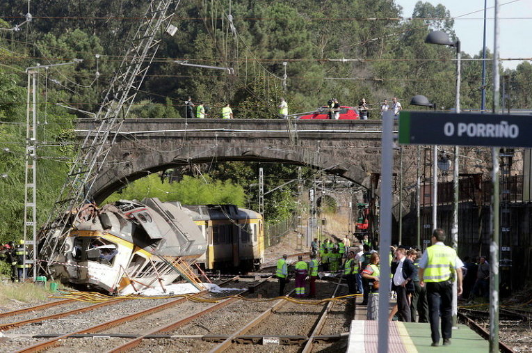Спасатели осматривают поезд, который сошел с рельсов в Галисии в Испании