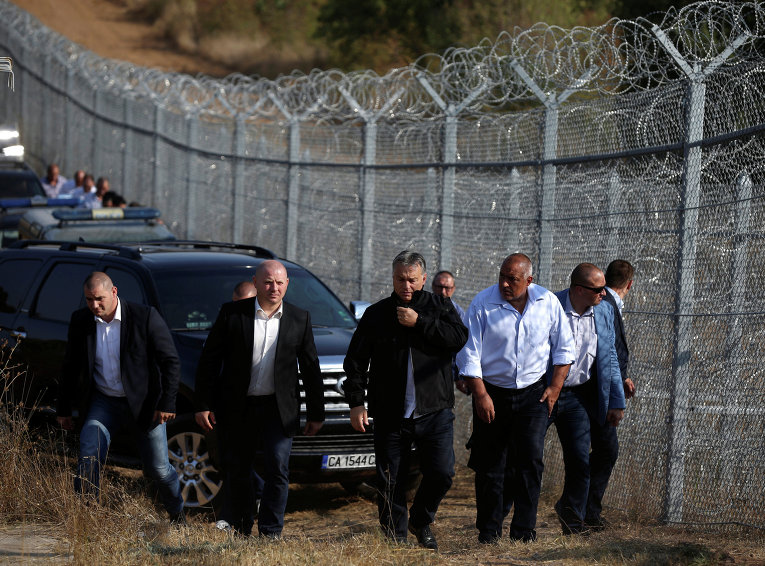 Премьер-министр Венгрии Виктор Орбан, слева, и его болгарский коллега Бойко Борисов, в центре, осматривают забор из колючей проволоки на границе от мигрантов.