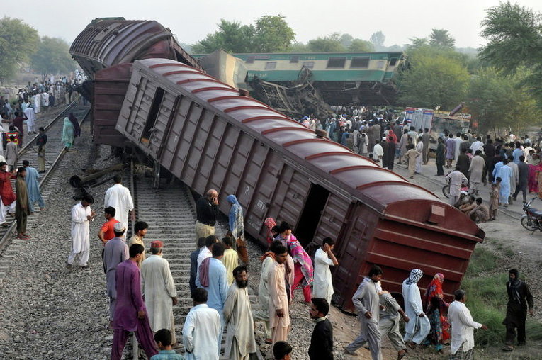 Местные жители собираются на месте, где столкнулись два поезда, Пакистан