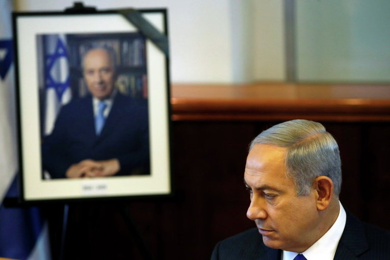 Премьер-министр Израиля Биньямин Нетаньяху сидит рядом с фотографией бывшего покойного президента Израиля Шимона Переса