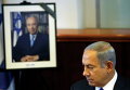 Премьер-министр Израиля Биньямин Нетаньяху сидит рядом с фотографией бывшего покойного президента Израиля Шимона Переса