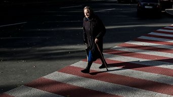 Пожилая женщина переходит улицу в Киеве