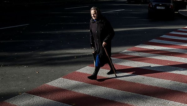 Пожилая женщина переходит улицу в Киеве