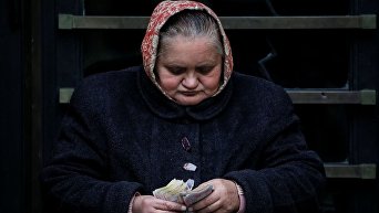 Пожилая женщина считает деньги в центре Львова