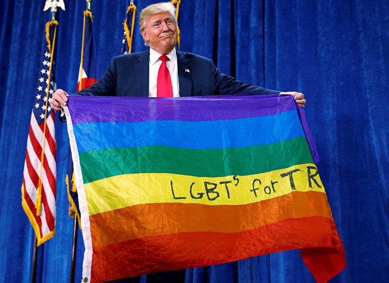 Кандидат в президенты США от республиканцев Дональд Трамп держит радужный флаг, на котором написано ЛГБТ за Трампа в ходе предвыборного митинга в городе Грили, штат Колорадо