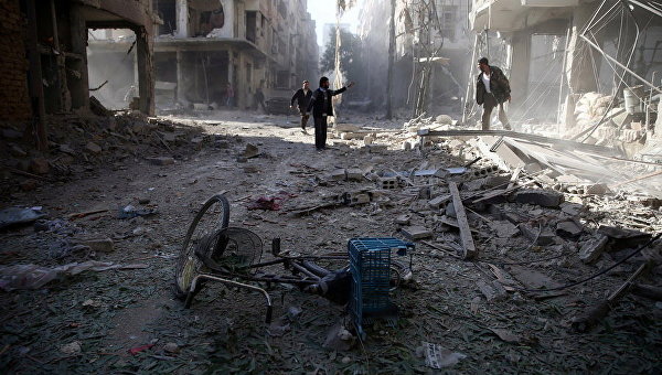 Мужчины осматривают поврежденный участок после авиаудара в осажденном повстанцами городе Думу, Сирия