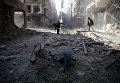 Мужчины осматривают поврежденный участок после авиаудара в осажденном повстанцами городе Думу, Сирия