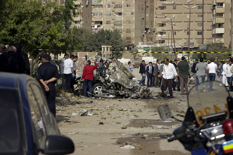 Египетские полицейские осматривают обломки автомобиля после того, как бомба взорвалась в столице Египте