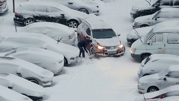 Мужчина убирает снег на парковке в Киеве