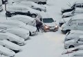 Мужчина убирает снег на парковке в Киеве
