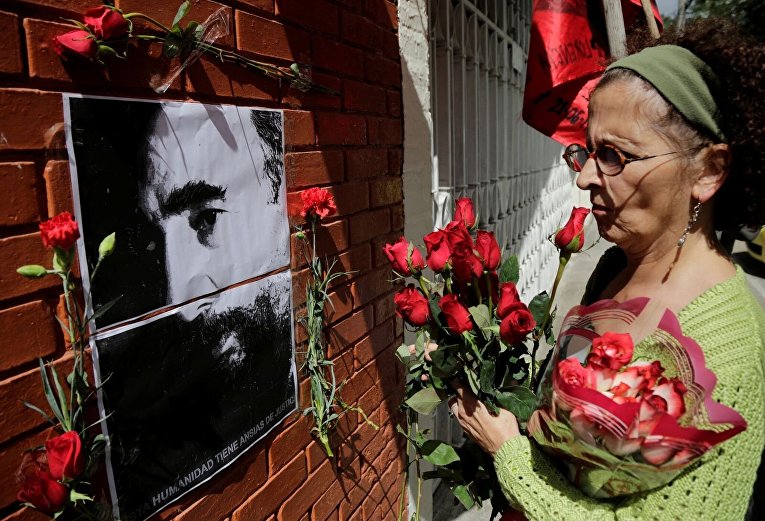 Женщина возлагает цветы возле посольства Кубы в Гватемале после объявления о смерти лидера кубинской революции Фиделя Кастро