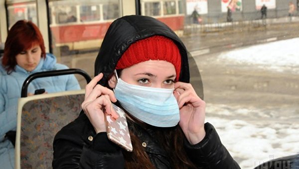 Девушка надевает маску в общественном транспорте. Архивное фото