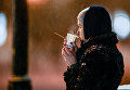 Девушка пьет кофе во время снегопада в Киеве