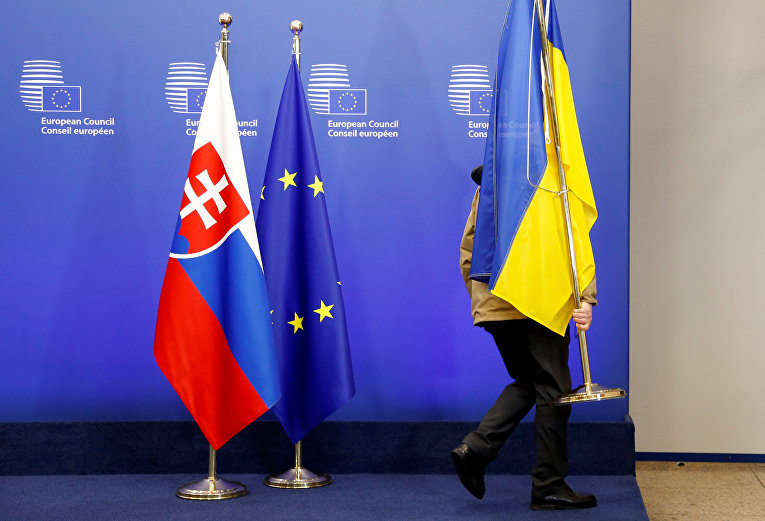 Чиновник снимает украинский национальный флаг с трибуны саммита Украина-ЕС в Брюсселе, Бельгия.