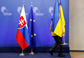 Чиновник снимает украинский национальный флаг с трибуны саммита Украина-ЕС в Брюсселе, Бельгия.