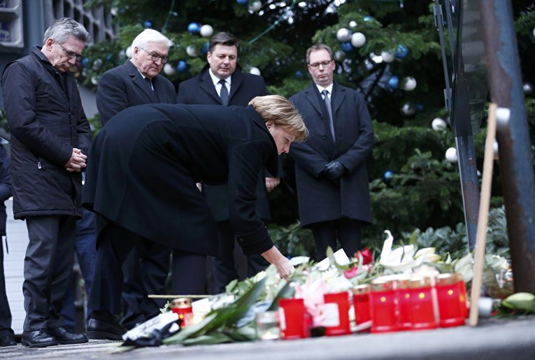 Канцлер Германии Ангела Меркель возлагает цветы на месте трагедии, случившейся накануне на рождественской ярмарке в Берлине.