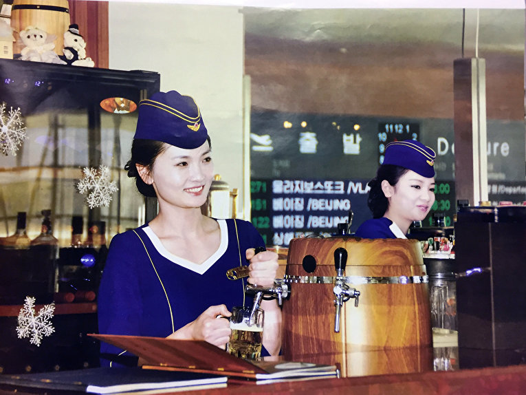 Молодая стюардесса, разливающая знаменитое местное пиво «Тэдонган».