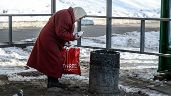 Пожилая женщина собирает пластиковые бутылки