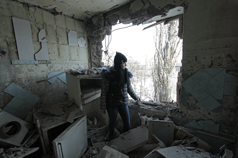 Девушка в квартире, разрушенной от попадания снаряда в результате обстрела, в Киевском районе Донецка