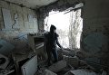 Девушка в квартире, разрушенной от попадания снаряда в результате обстрела, в Киевском районе Донецка