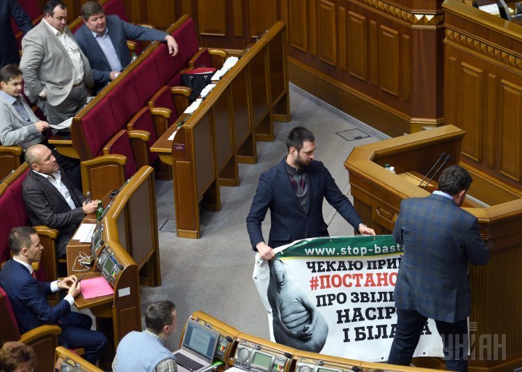 Народные депутаты снимают плакат с трибуны парламента во время заседания Верховной Рады Украины