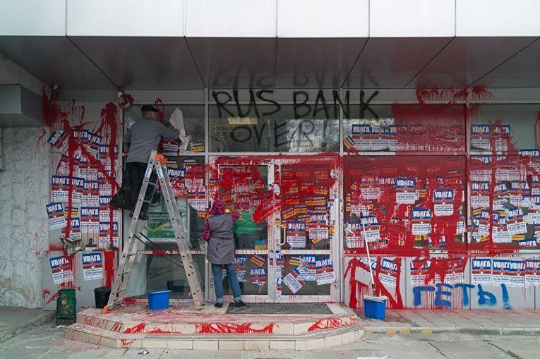 В Днепре разблокировали российские банки: рабочие отмывают краску и отклеивают плакаты
