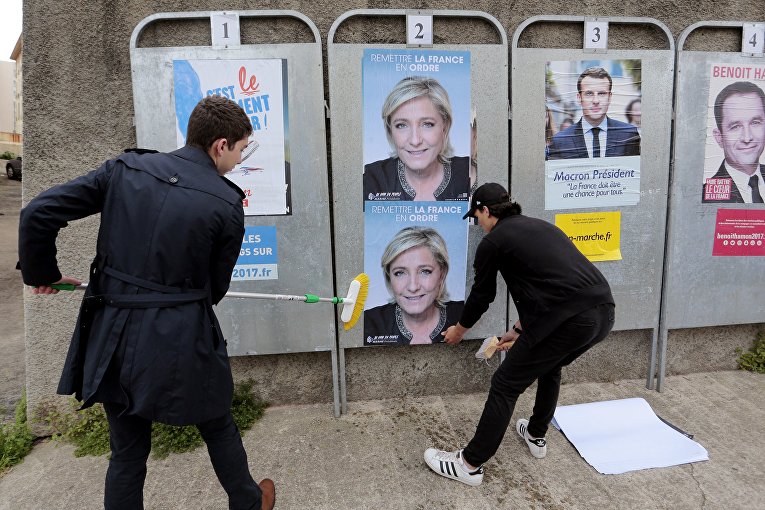 Члены французской ультраправой партии Фронт национального молодежного движения клеят плакаты с французским кандидатом в президенты Марин Ле Пен