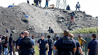 Французская полиция и мигранты в точке распространения продовольствия в Кале