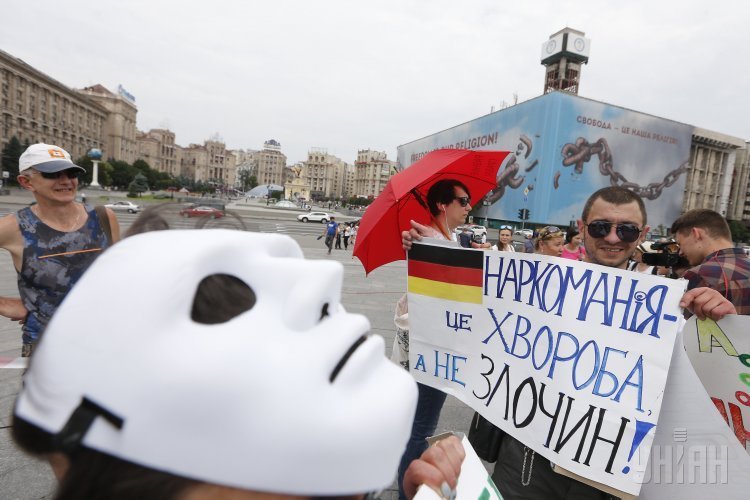 Мужчина держит плакат во время перформанса в Киеве Грабли украинской наркополитики, которая прошла в рамках Международного дня против употребления наркотиков и Международного дня поддержки жертв пыток.