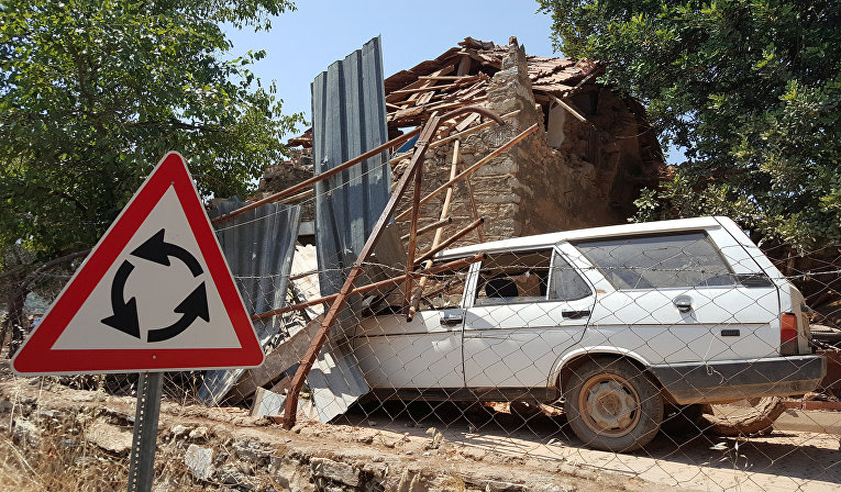 Поврежденный автомобиль и дом видны после землетрясения в одной из деревень в Турции
