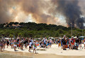 Туристы в спешке эвакуируются с пляжа из-за пожара на склоне в Борм-ле-Мимозасе в департаменте Вар, Франция.