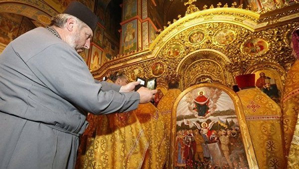 Священник фотографирует икону Пресвятой Богородицы - покровительницы украинских военных.