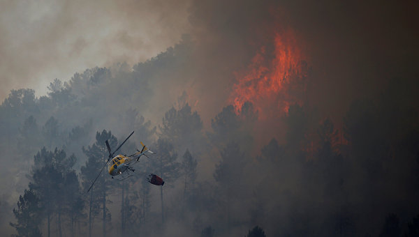 Пожарный вертолет опускает воду, чтобы погасить лесной пожар в Вила-Велья-де-Рдао, недалеко от Каштелу-Бранку, Португалия