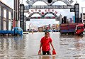 Люди ходят через затопленную территорию на рынке строительных материалов в Харбине, провинция Хэйлунцзян, Китай