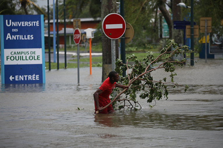 Мужчина удаляет ветку на затопленной улице после урагана Марии на острове Гваделупа