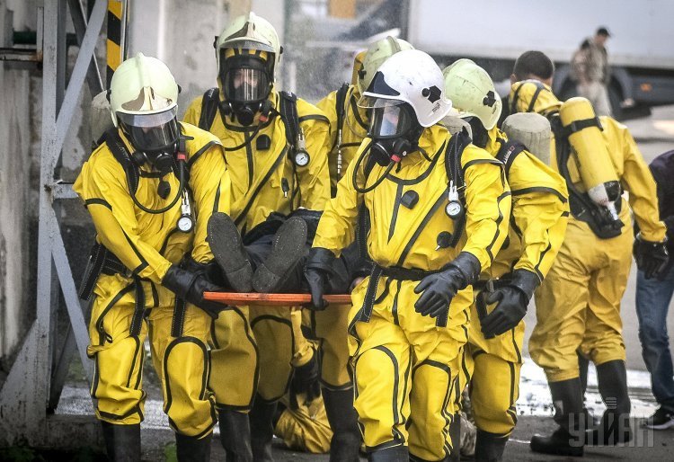 Спасатели несут условно пострадавшего во время совместных учений спасательных служб столицы по ликвидации последствий аварии на химически опасном объекте на территории ЧАО Укррыба.